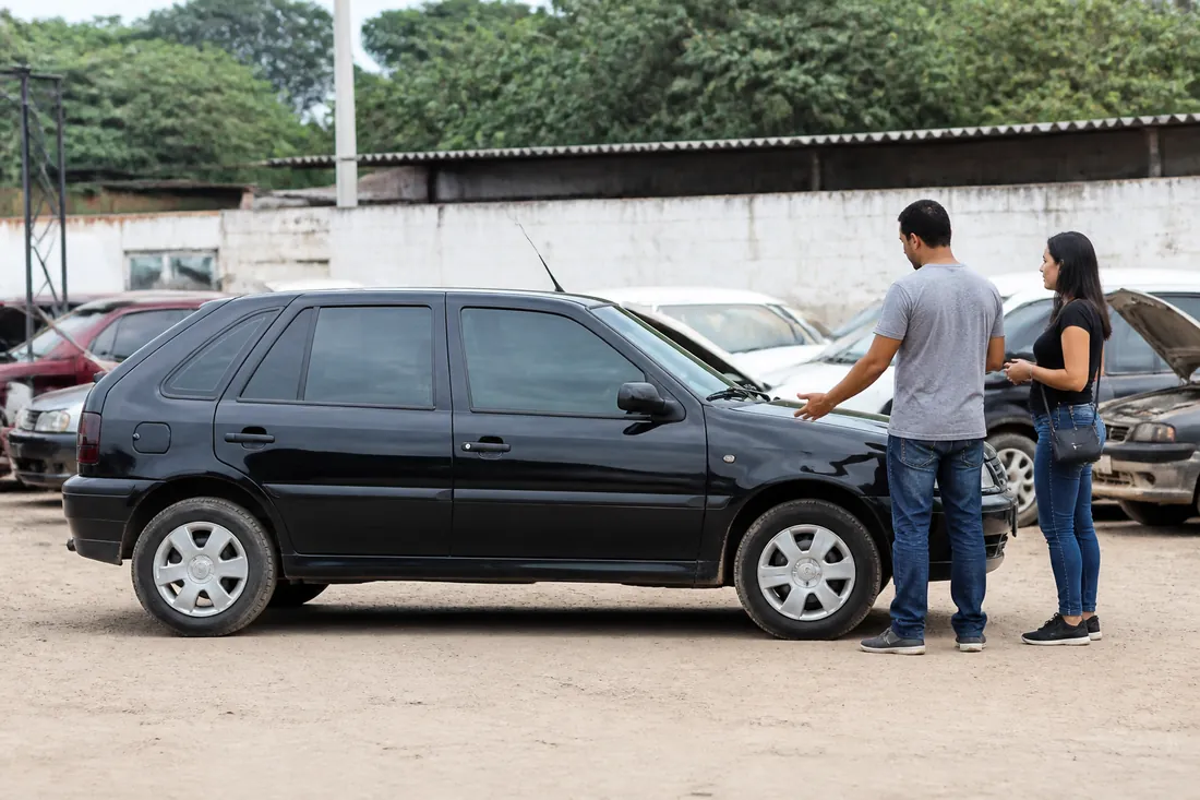 Casal avaliando um carro usado em um pátio de vendas